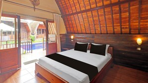 A wooden-framed bedroom with a large bed, a view of the outside, and a ceiling fan. - OYO 94782 Loka Loka Ubud (Ubud)