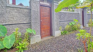 A stone building with a wooden door, surrounded by tropical plants and a gravel pathway. - OYO 94782 Loka Loka Ubud (Ubud)
