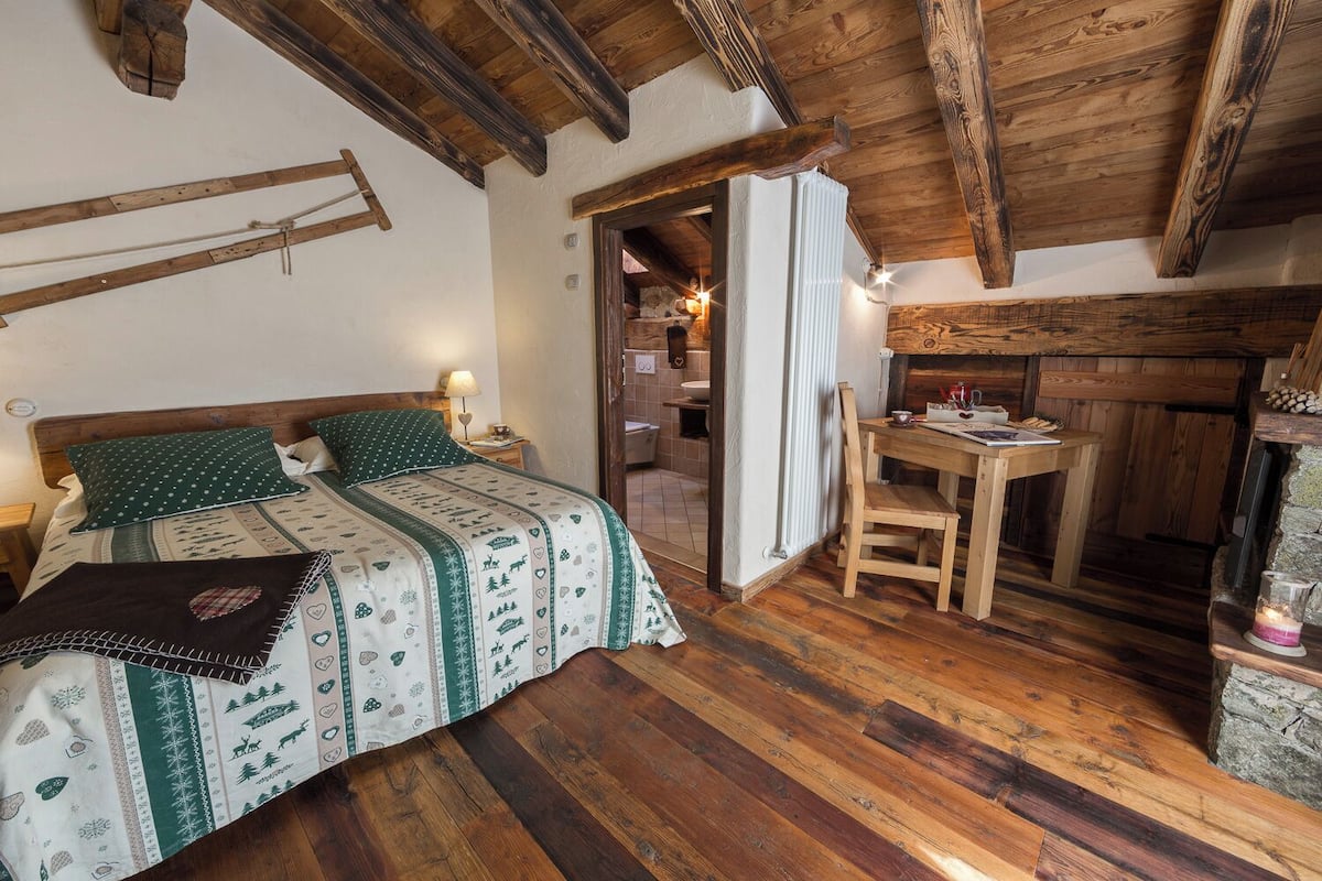 Ein gemütliches Zimmer mit einem hölzernen Bett, einem kleinen Tisch und einem Kamin.