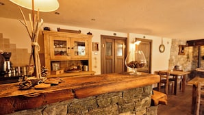 Une cuisine rustique avec un comptoir en bois, un mur en pierre et un meuble avec des portes en verre.