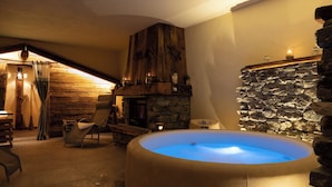 Une pièce chaleureuse avec un mur en pierre, une cheminée et un jacuzzi.
