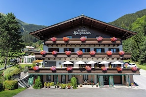 A two-story building with balconies adorned with flower baskets, a visible clock, and a sign reading 'Pension Margarete.' - Pension Margarete (Zell am See)