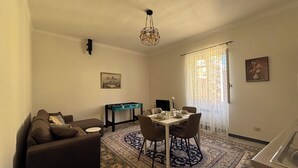 A compact living space with a dining area, a sofa, a table set for four, and a patterned rug. - Three-room apartment just a few steps from the beaches in the center of Imperia (Imperia)