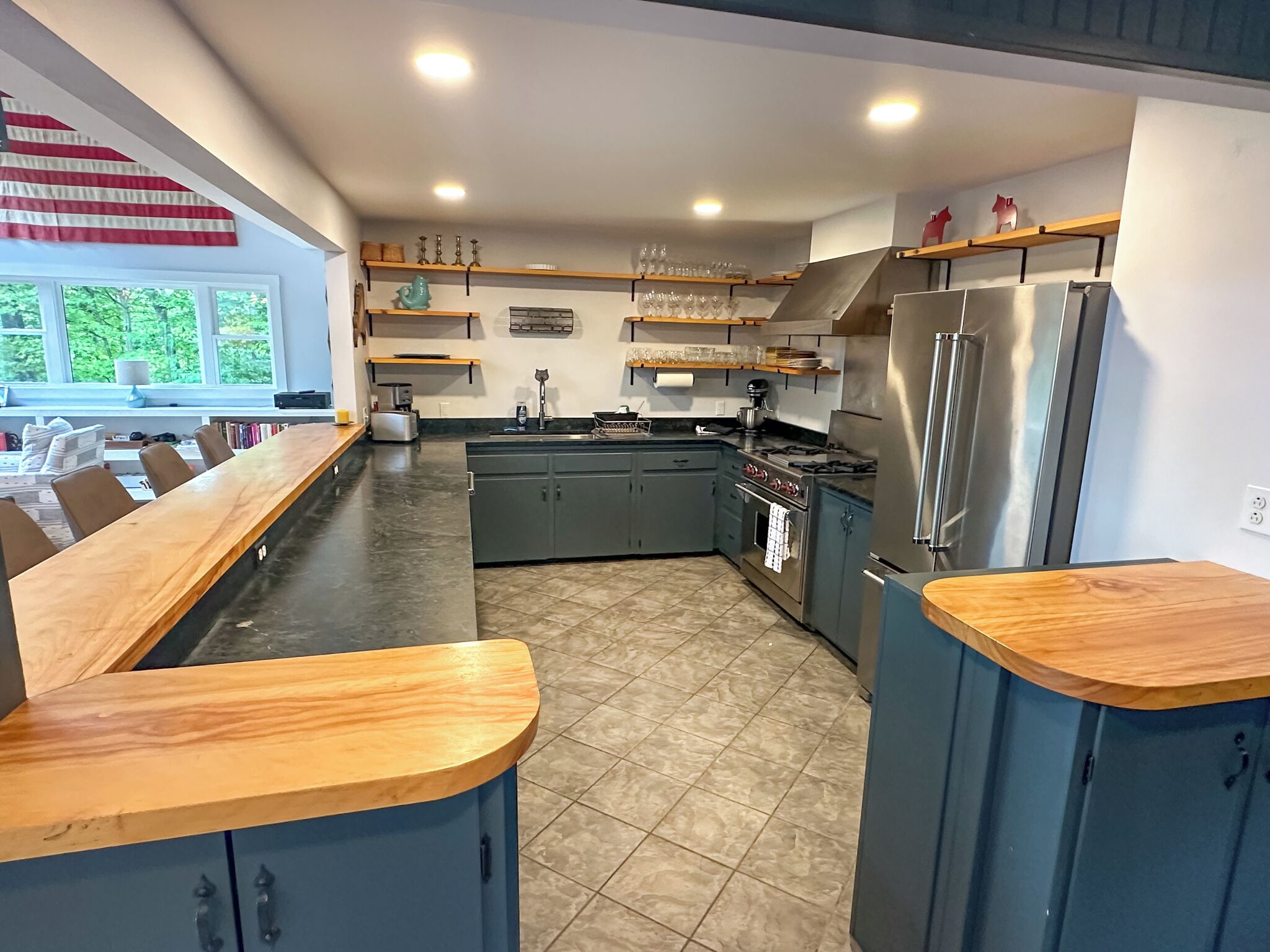 Een moderne keuken met een lange houten aanrecht, ingebouwde kasten en een roestvrijstalen koelkast.
