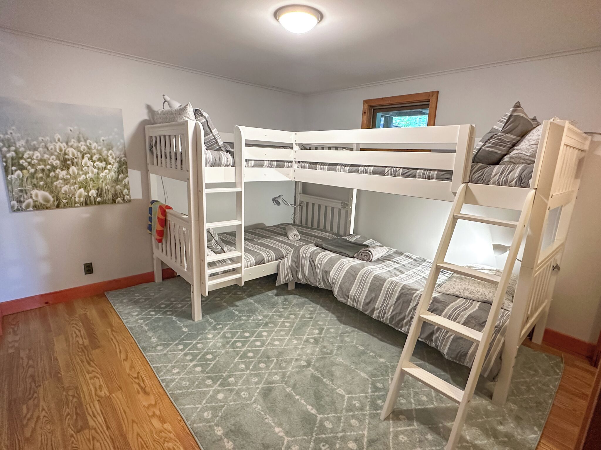 A bunk bed room with a patterned rug, a radiator, and a window.