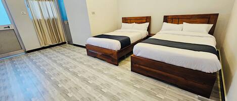 A hotel room with two wooden beds, a light-colored tiled floor, and a window with curtains.