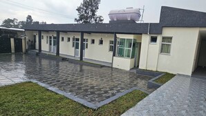 A modern building with a tiled courtyard, a covered walkway, and a large air conditioning unit on the roof. - Cozy villa (Addis Ababa)