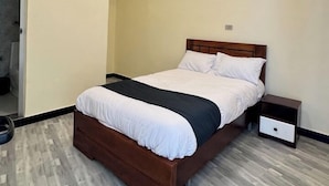 A modern bedroom with a wooden bed, a bedside table, and a built-in bench. - Cozy villa (Addis Ababa)