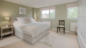 Een slaapkamer met een bed, nachtkastjes, een stoel en een radiator.