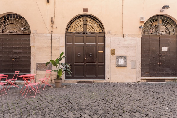 A building with a large central door, two smaller doors, and a potted plant in front.