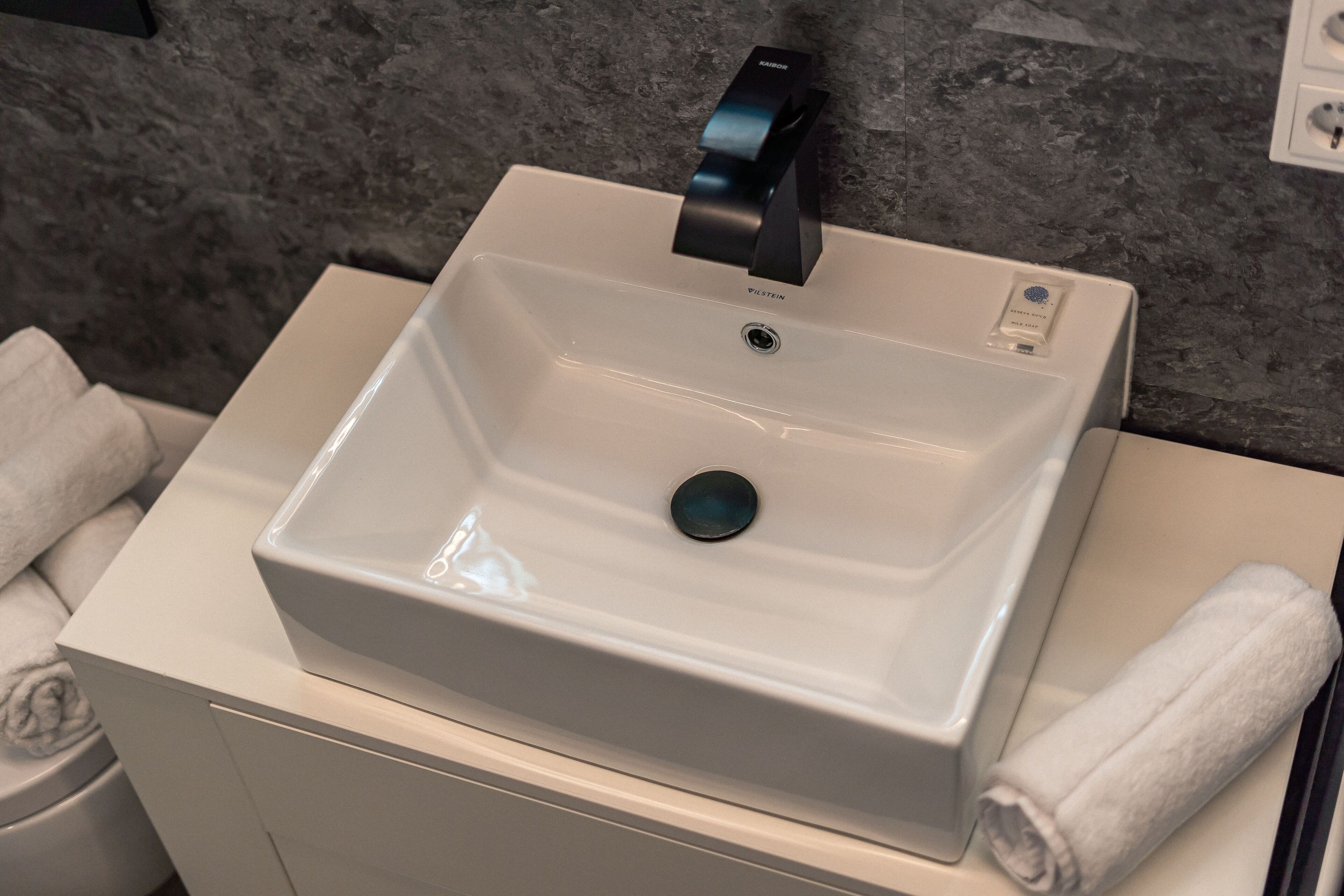 A bathroom sink with a modern faucet, a visible drain, and a towel on the side.
