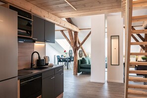 A modern kitchen with built-in appliances, wooden beams, and a dining area with a green sofa.