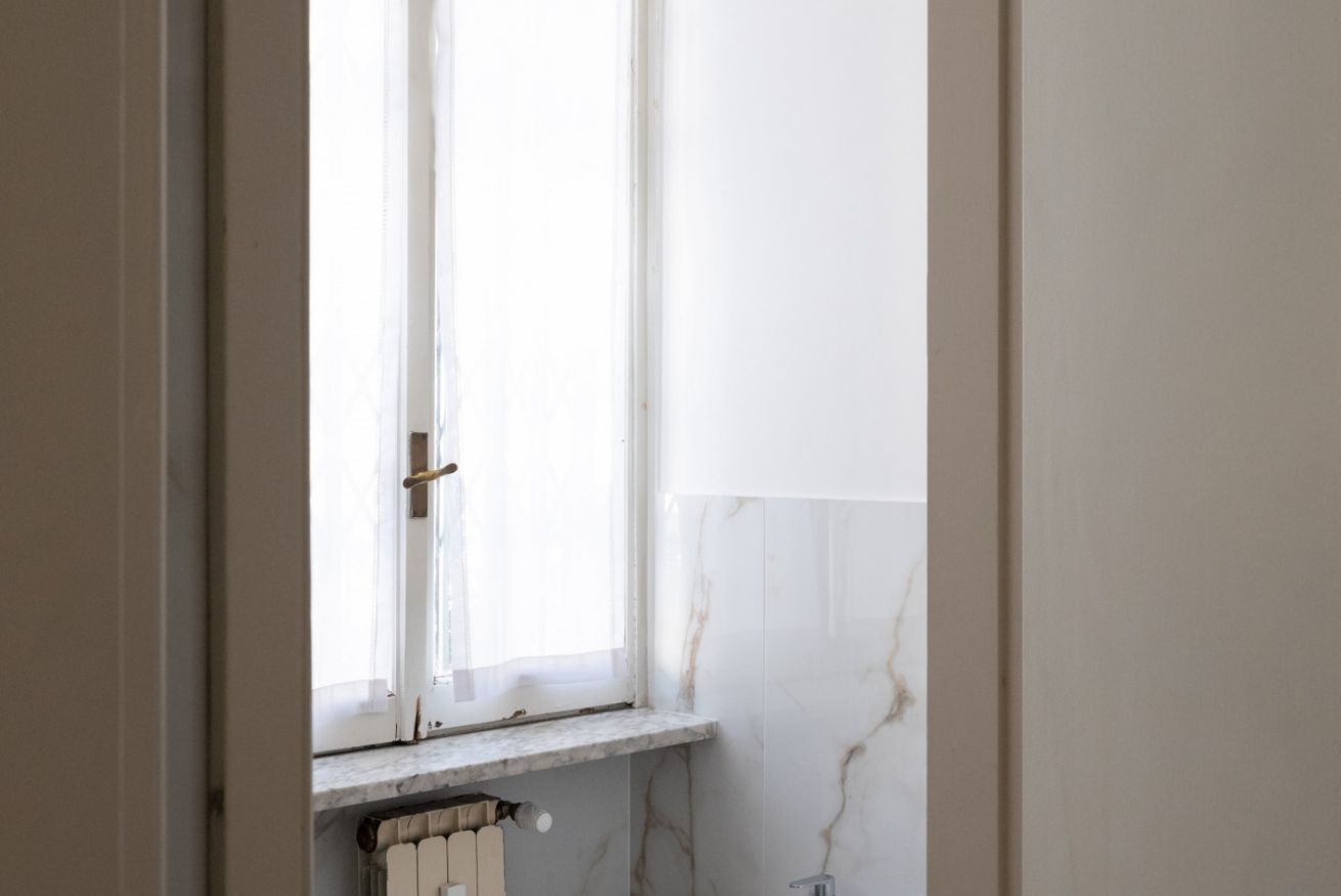 A bathroom with a window, a radiator, and a marble wall.
