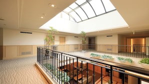 A spacious atrium with a high ceiling, a central glass skylight, and a black railing. - Villa The Club Gotemba West (Gotemba)