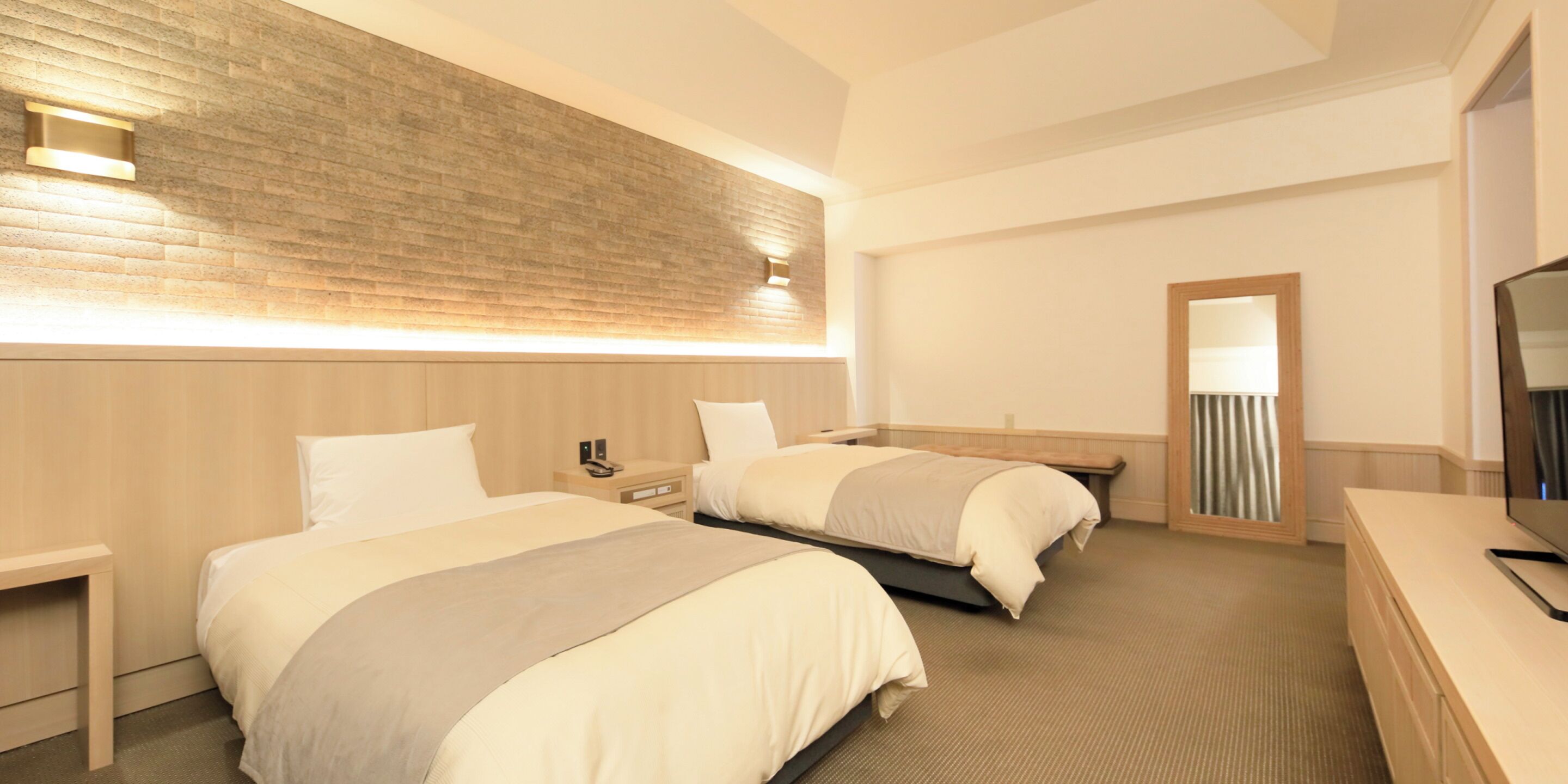A hotel room with two beds, a wooden headboard, a nightstand, a desk, and a television.