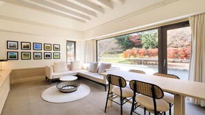 A modern living room with a sofa, a dining table with chairs, a TV, and framed pictures on the wall. - Villa The Club Gotemba West (Gotemba)