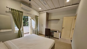 A bedroom with a bed, a desk, a chair, and a wardrobe. - SS LUMINA VILLA (Bangalore)