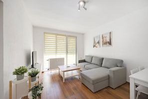 Un salon avec un canapé, une table basse, un téléviseur et des plantes en pot.