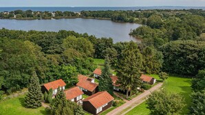 A cluster of houses with red roofs, surrounded by lush greenery and a lake. - Quiet bungalow in Bansin with garden & WLAN - suitable for families & dogs (Seebad Bansin)