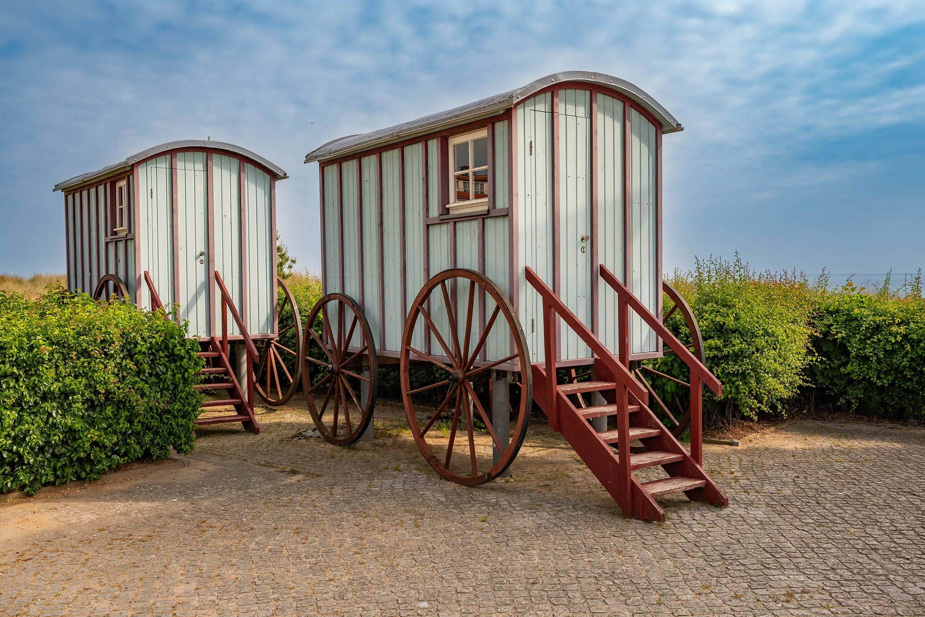Zwei hölzerne Strukturen auf Rädern mit Treppen, vermutlich historisch oder dekorativ.