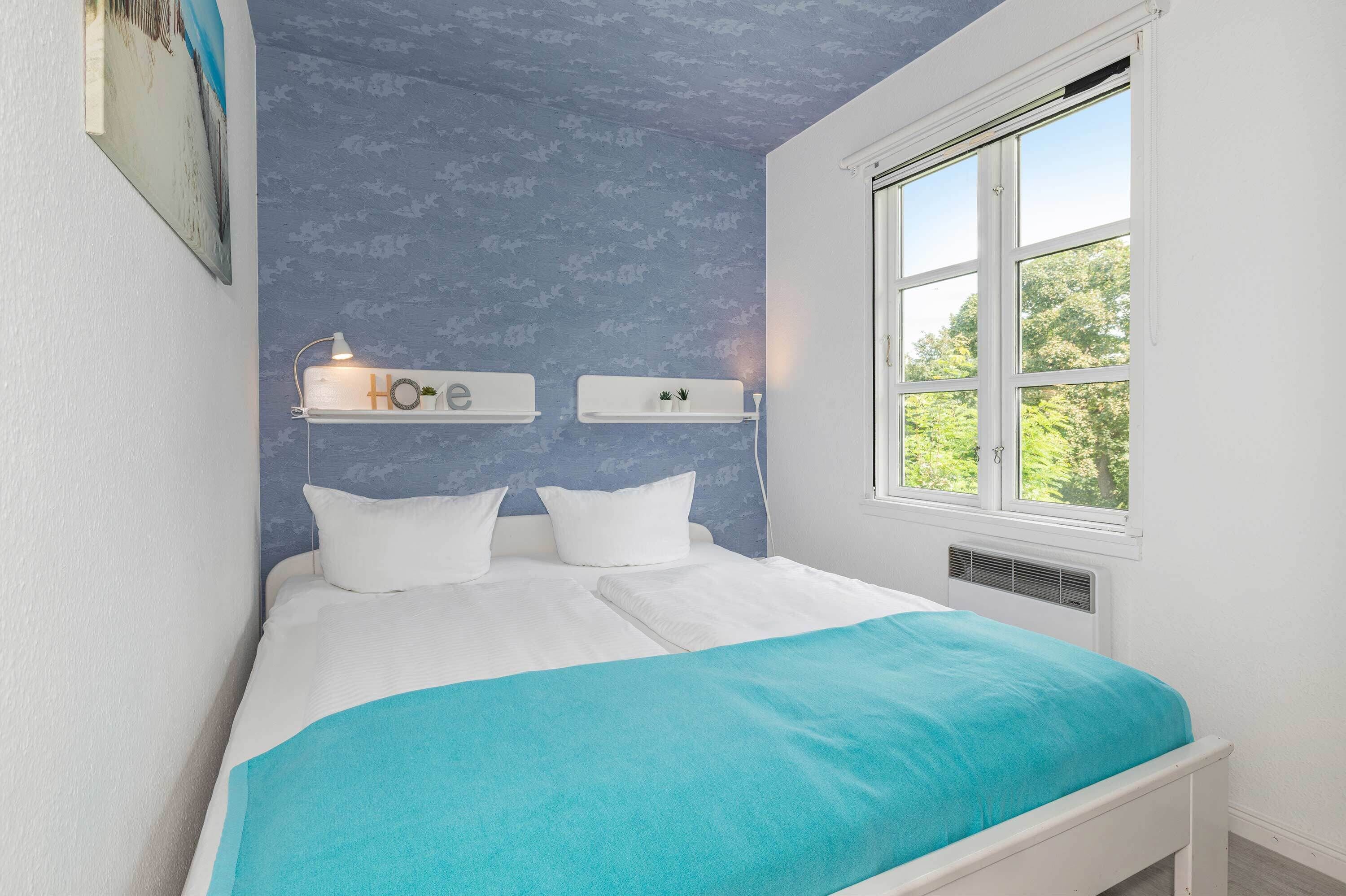 Un dormitorio con una cama, dos mesitas de noche, una ventana y una estantería en la pared.