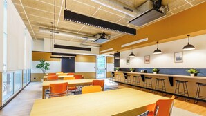 A modern conference room with a long table, orange chairs, and a bar area with stools. - Student Factory Nancy Centre (Nancy)