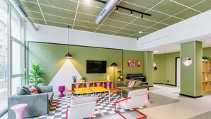 A modern living room with a checkered floor, grey sofa, and a small table with colorful chairs. - Student Factory Nancy Centre (Nancy)