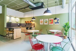 Une cuisine moderne dotée d’un îlot central, d’un coin repas avec des chaises aux couleurs vives et d’une grande fenêtre qui laisse entrer la lumière naturelle.