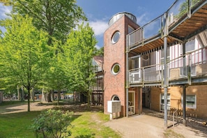 A multi-story building with a brick facade, circular windows, and a balcony with a metal railing.