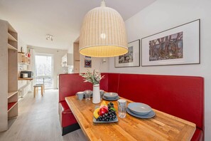 A modern kitchen with a wooden countertop, a red bench, and a dining table set with plates, glasses, and a fruit bowl. - Beautiful vacation apartment in Koserow with terrace - only 50 m to the sea (Koserow)