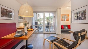 Un salon moderne comprenant un coin repas, un canapé rouge, une table en bois, une chaise noire et des œuvres d’art accrochées aux murs.