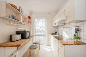 A kitchen with a wooden countertop, a toaster, a kettle, and a window with a view of trees.