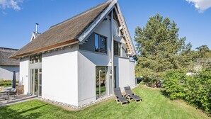 A modern house with a sloped roof, large windows, and a well-maintained lawn.