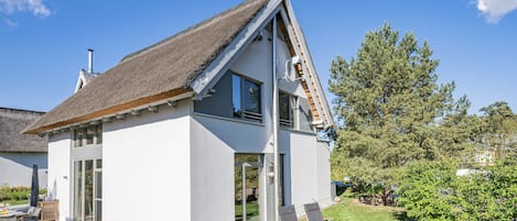 A modern house with a sloped roof, large windows, and a well-maintained lawn.