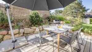 An outdoor patio with a table set for dining, surrounded by chairs.