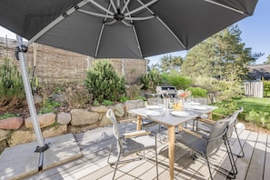 An outdoor patio with a table set for dining, surrounded by chairs.