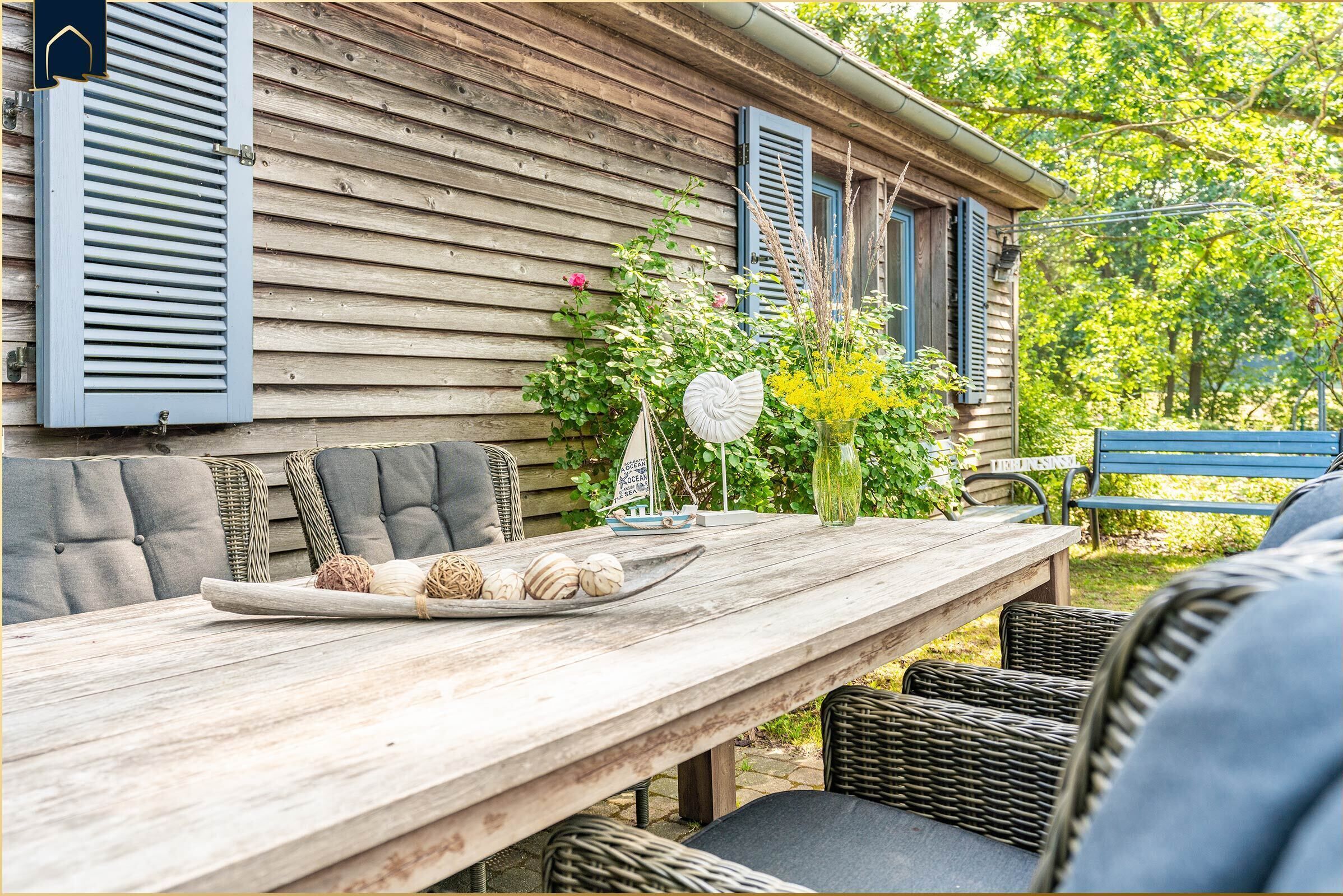 A wooden dining table with wicker chairs, a decorative plate with eggs, and a vase with flowers.