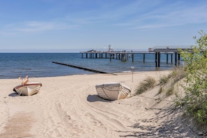A beach with a pier, two boats, and a wooden walkway. - Modern vacation apartment with terrace, just 750 m from the Baltic Sea beach (Koserow)