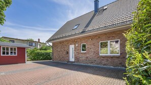 A brick house with a tiled roof, a small attached garage, and a paved driveway.