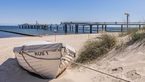A boat named 'KUS 1' tied to a sandbar near a pier.