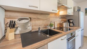 A modern kitchen with a black sink, stainless steel appliances, and wooden cabinetry.