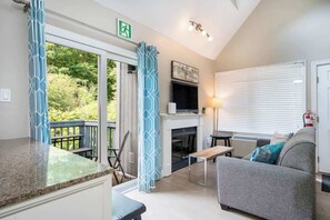 A cozy living room with a fireplace, a sofa, a coffee table, and a view of the outdoors. - Whispering Pines | Hot Tub & Shuttle w/ Patio (The Blue Mountains)