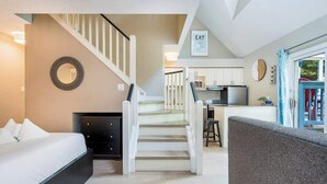 A modern interior with a staircase leading to a kitchen, a dining area, and a living space with a sofa.