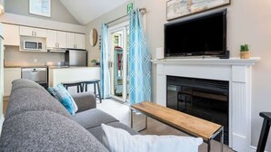 A modern living room with a grey sofa, a wooden coffee table, a flat-screen TV, and a fireplace.