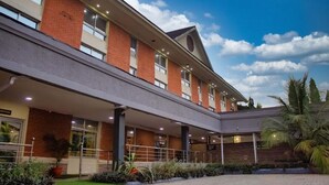 Ein modernes Hotel mit überdachter Einfahrt, mehreren Stockwerken und einer begrünten Anlage mit Pflanzen.