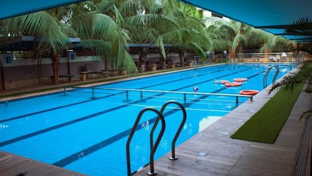 Ein Swimmingpool mit klarem, blauem Wasser, umgeben von Palmen und Liegestühlen.