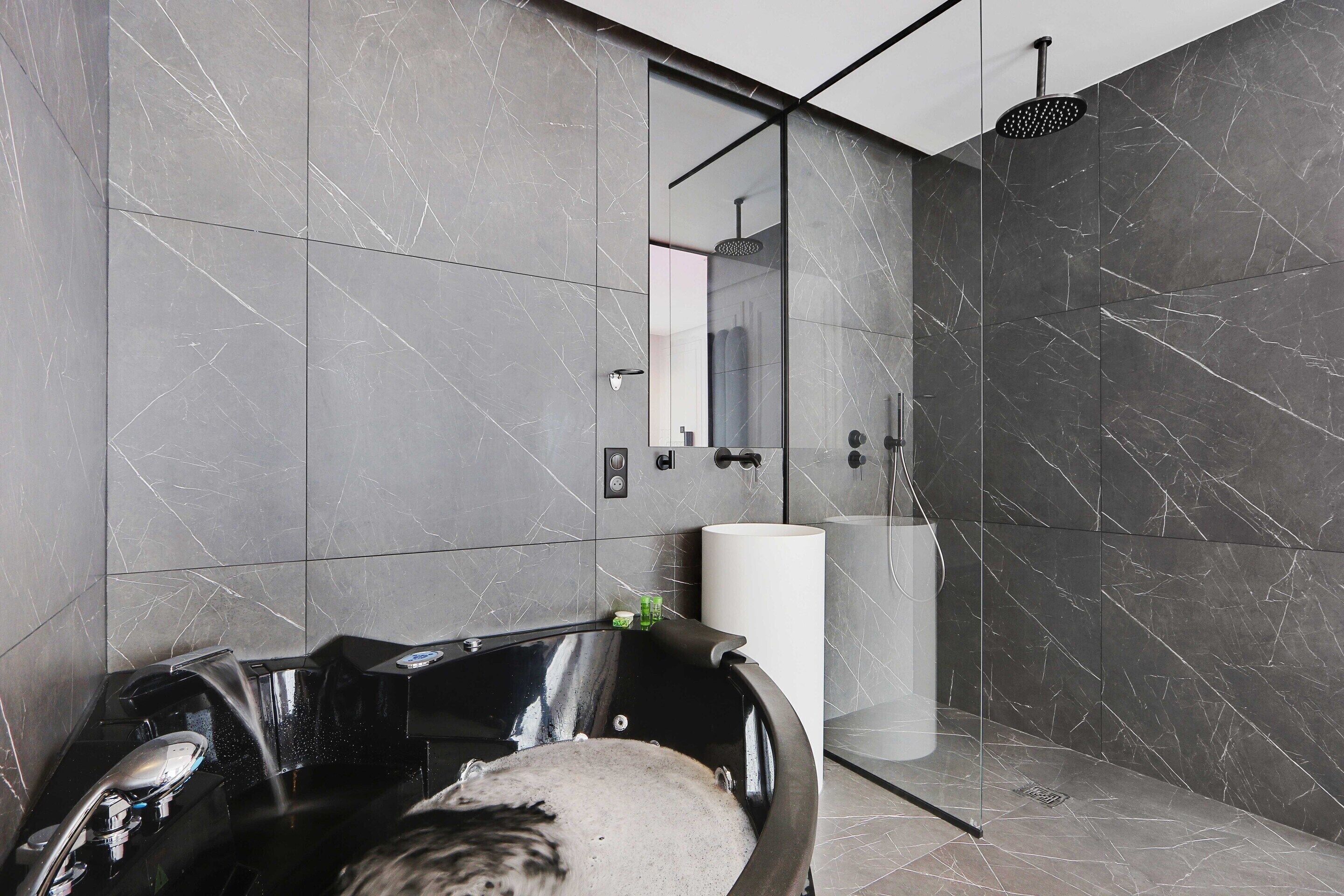 A modern bathroom with a freestanding bathtub, a large mirror, and a shower area.