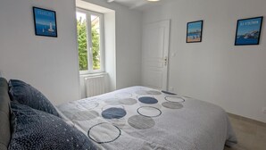 A bedroom with a bed, a window, and two framed pictures on the wall. - Renovated Charentais house in peaceful setting with parking and private garden (Challignac)