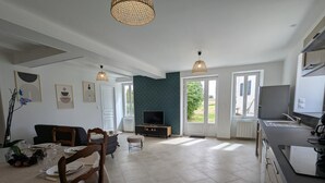 A modern kitchen with a dining area, large windows, and a television. - Renovated Charentais house in peaceful setting with parking and private garden (Challignac)