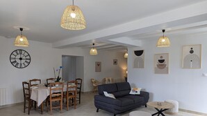 A spacious living area with a dining table, sofa, and decorative wall art. - Renovated Charentais house in peaceful setting with parking and private garden (Challignac)